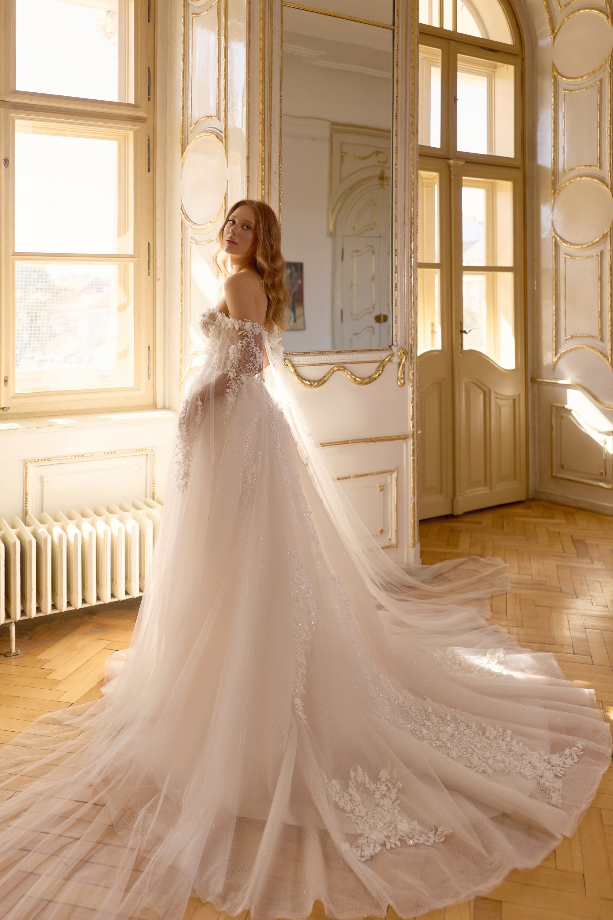 Ivory wedding dress with a full tulle skirt, floral lace detailing, off-the-shoulder sleeves, and a long train