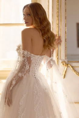 Lace-up corset back on an ivory wedding dress with off-the-shoulder sheer sleeves and floral appliqués