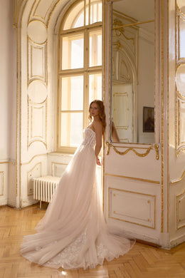 Side silhouette of an ivory ball gown wedding dress with a sweeping tulle train and floral lace hem