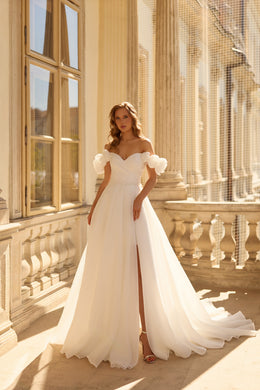 Ivory A-line wedding dress with a sweetheart neckline, puff sleeves, front slit, and flowing train