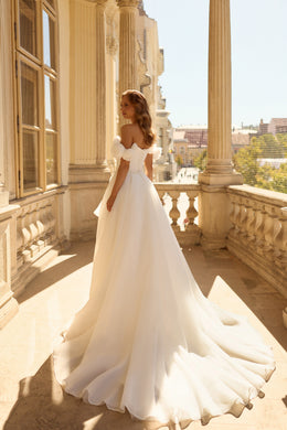Ivory wedding dress showing an open back, off-the-shoulder puff sleeves, and a sweeping train