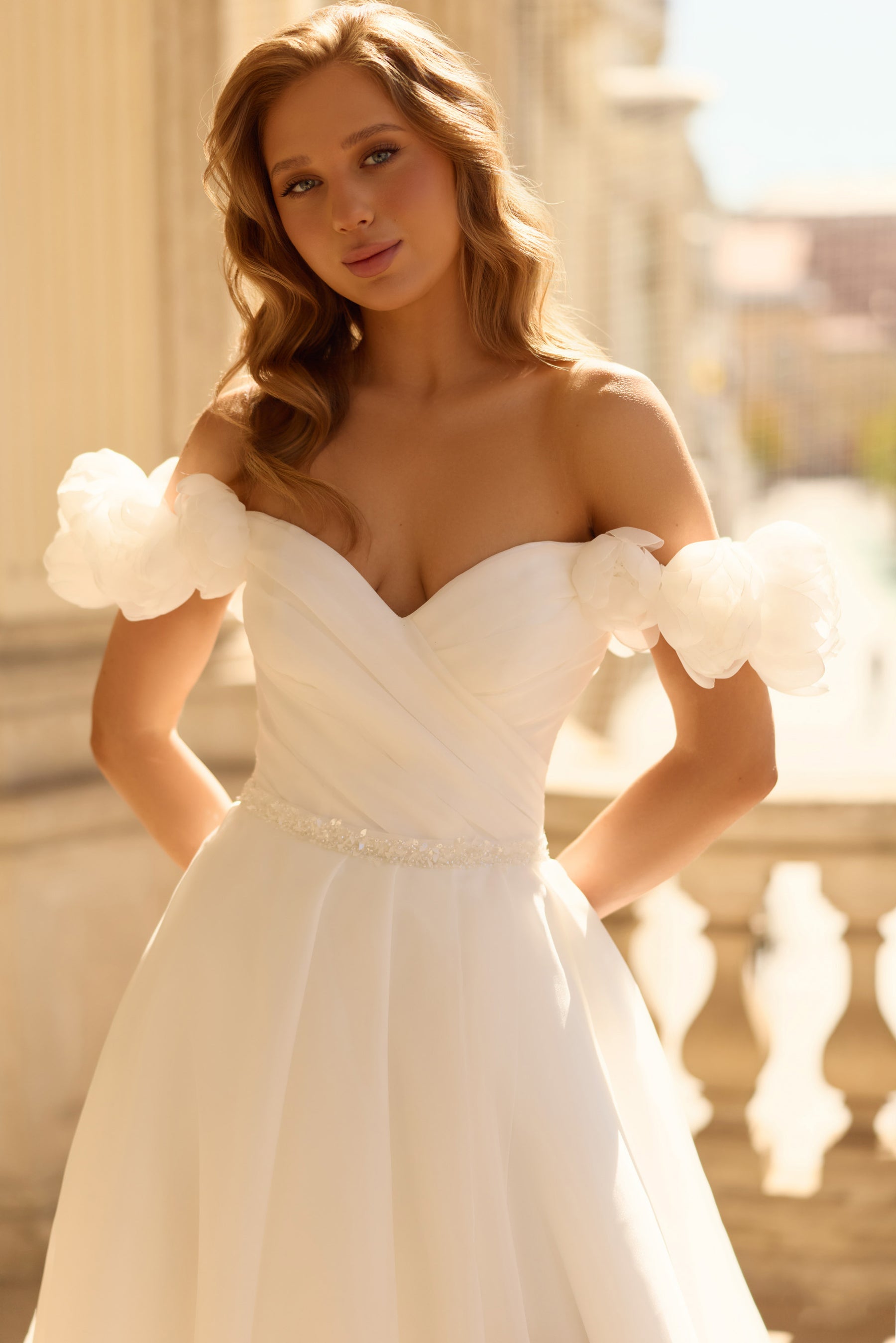 Close-up of an ivory wedding dress with a ruched sweetheart neckline, puff sleeves, and beaded waist