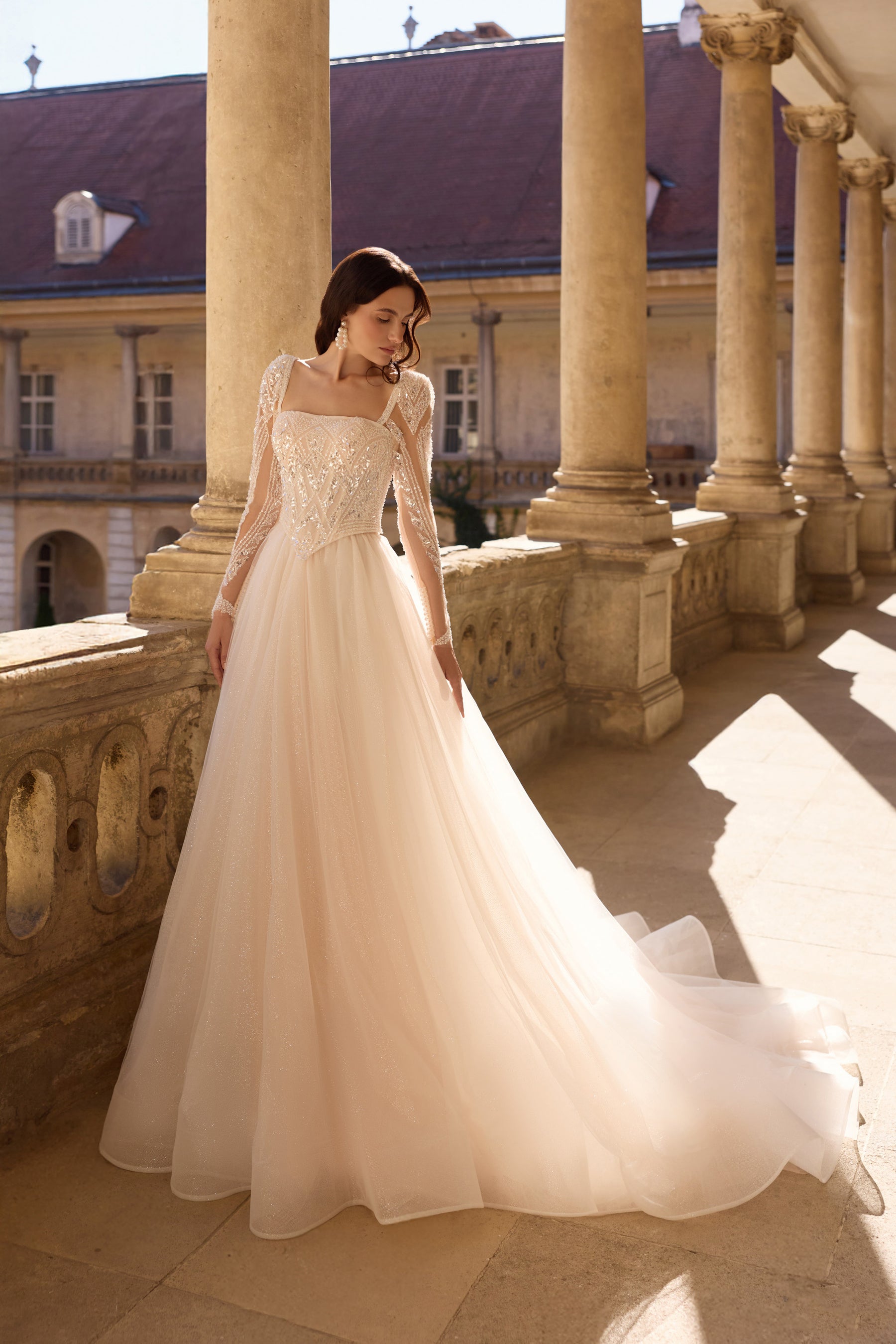 Ivory A-line wedding dress with sparkling beaded bodice, sheer long sleeves, and a flowing train