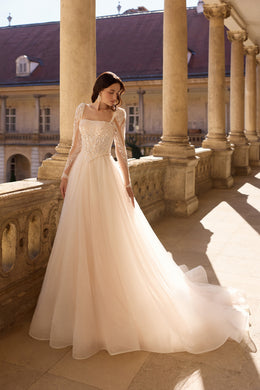 Ivory A-line wedding dress with sparkling beaded bodice, sheer long sleeves, and a flowing train
