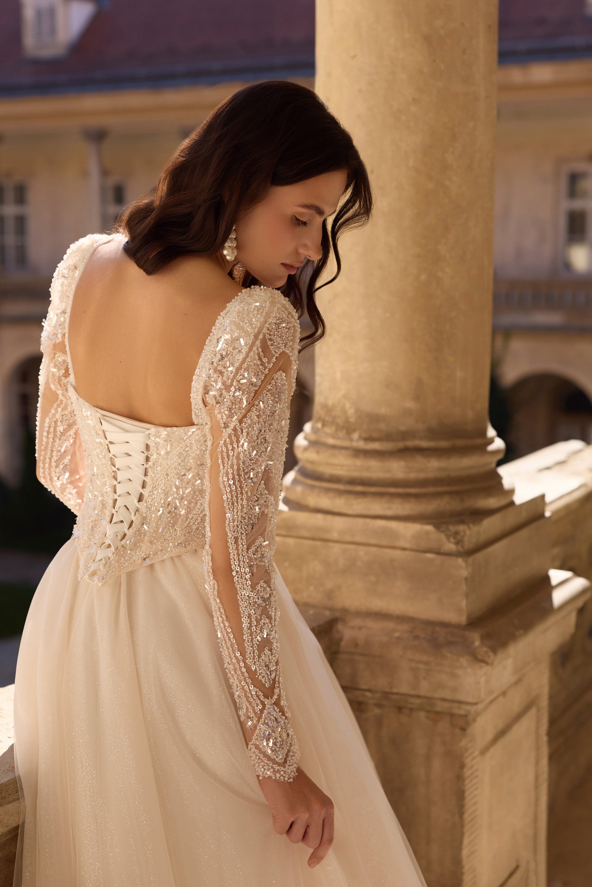 Square open back with corset lacing and sheer lace sleeves on an ivory wedding dress