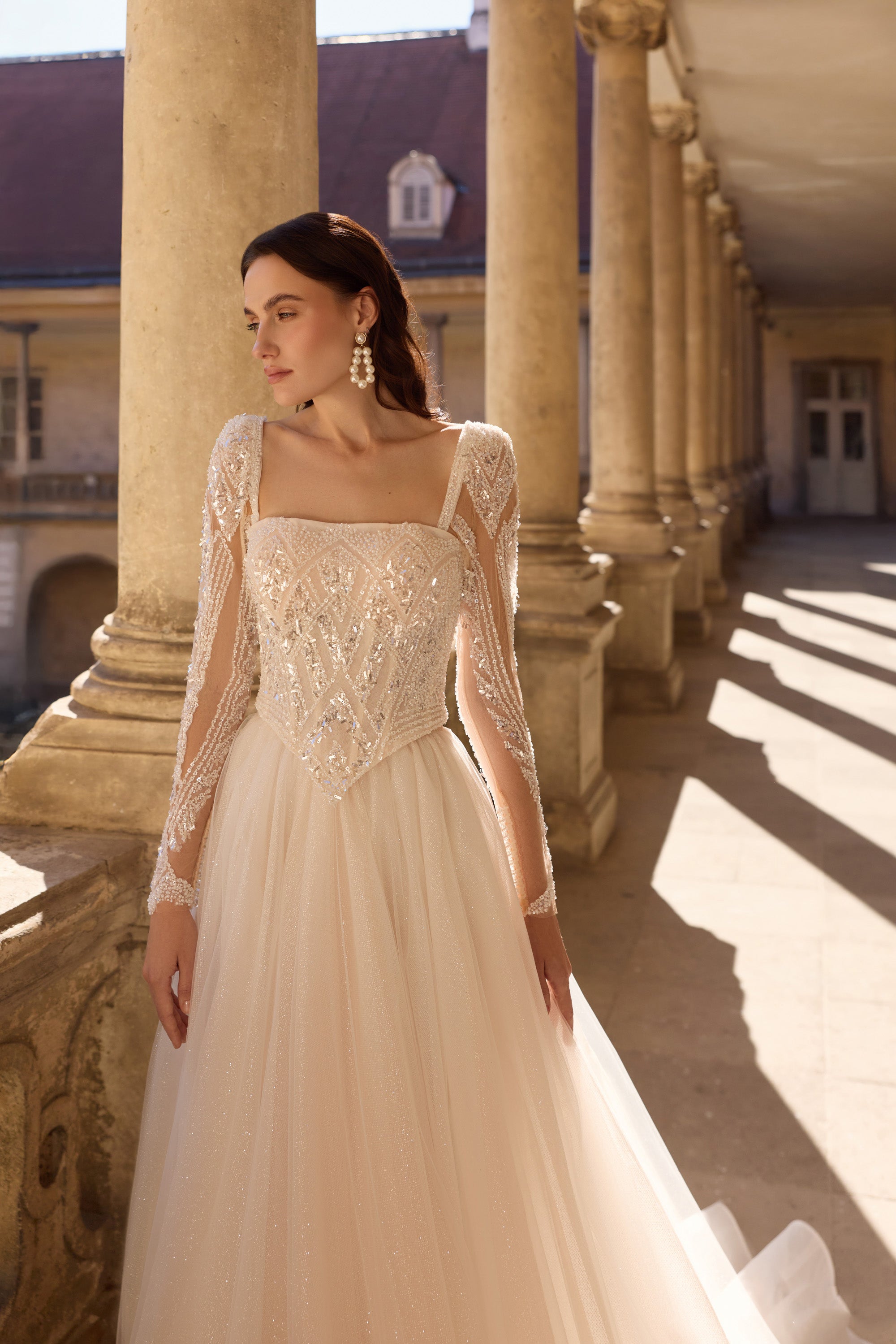 Ivory A-line wedding dress with a square neckline, sheer embellished sleeves, and a beaded bodice