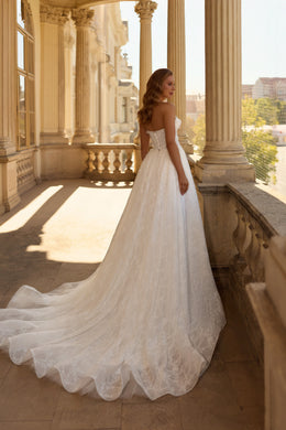 Ivory wedding dress showing a low open back, fitted bodice, A-line skirt, and sweeping scalloped lace train