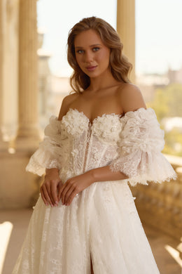 Close-up of an ivory wedding dress with floral lace appliqués, corset-style bodice, sweetheart neckline, and puff sleeves