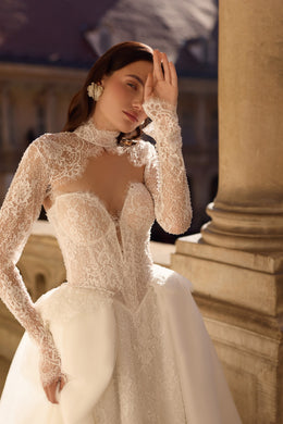 Close-up of an ivory wedding dress with an illusion lace neckline, long sleeves, and sweetheart cups