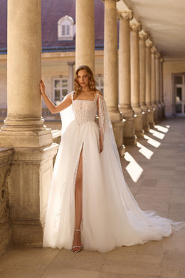 Ivory wedding dress with a beaded square-neck bodice, high front slit, and sweeping sheer cape train