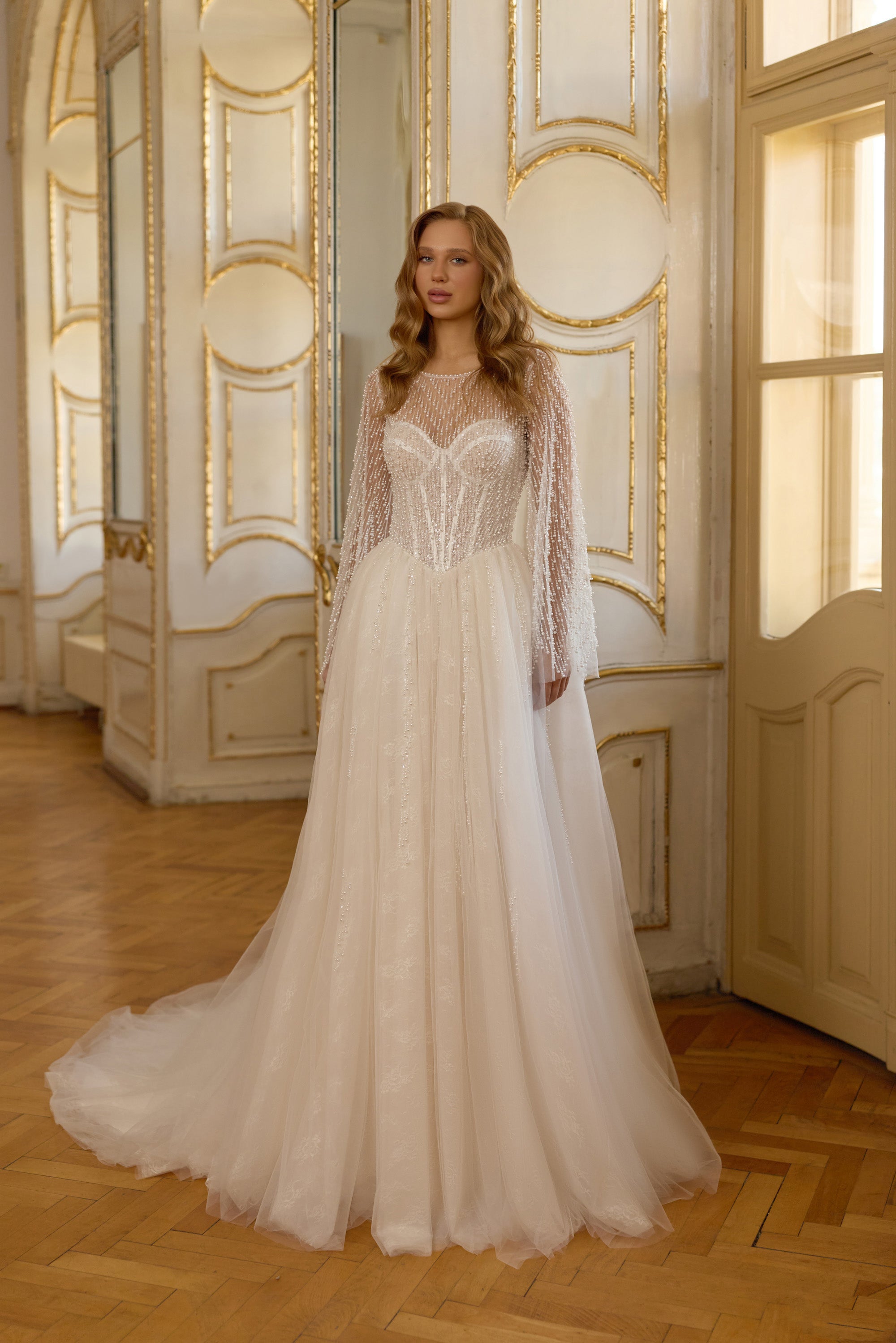 Ivory A-line wedding dress with sheer beaded long sleeves, illusion neckline, and flowing train