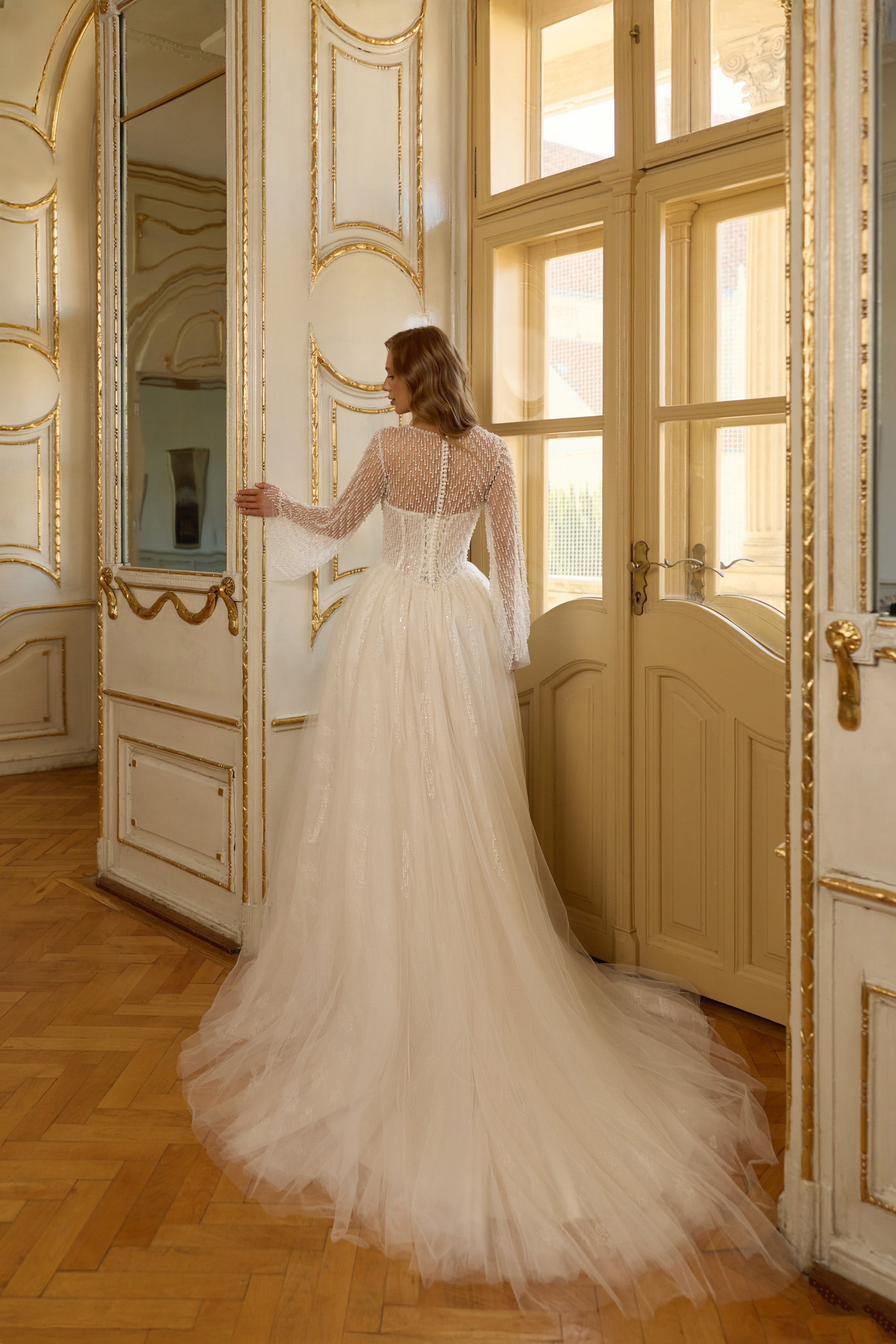 Sheer beaded back and long train on an ivory A-line wedding dress