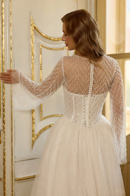 Close-up of the sheer beaded back, long sleeves, and fitted waist on a wedding dress