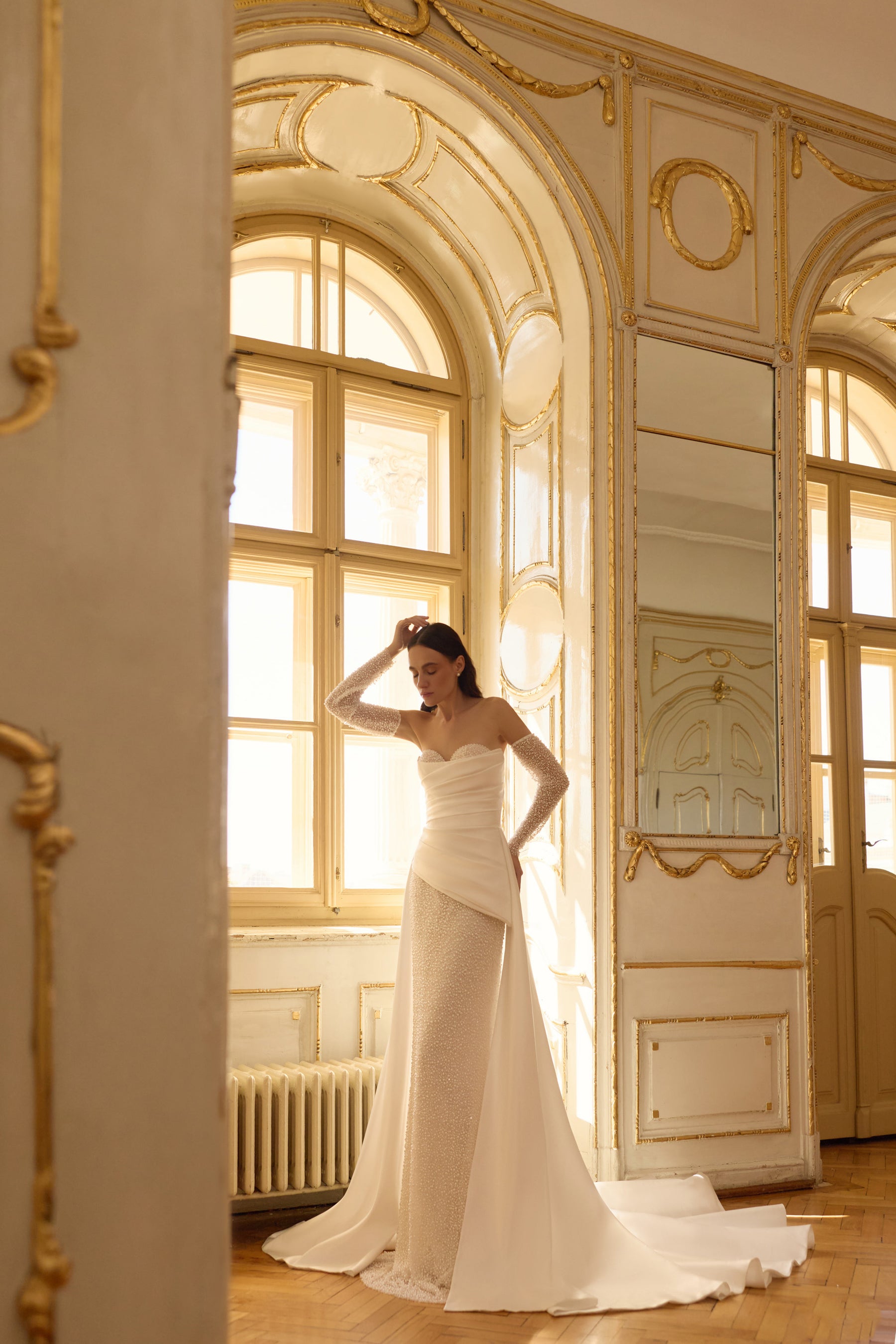 Ivory beaded mermaid wedding dress with a strapless neckline and flowing satin overskirt