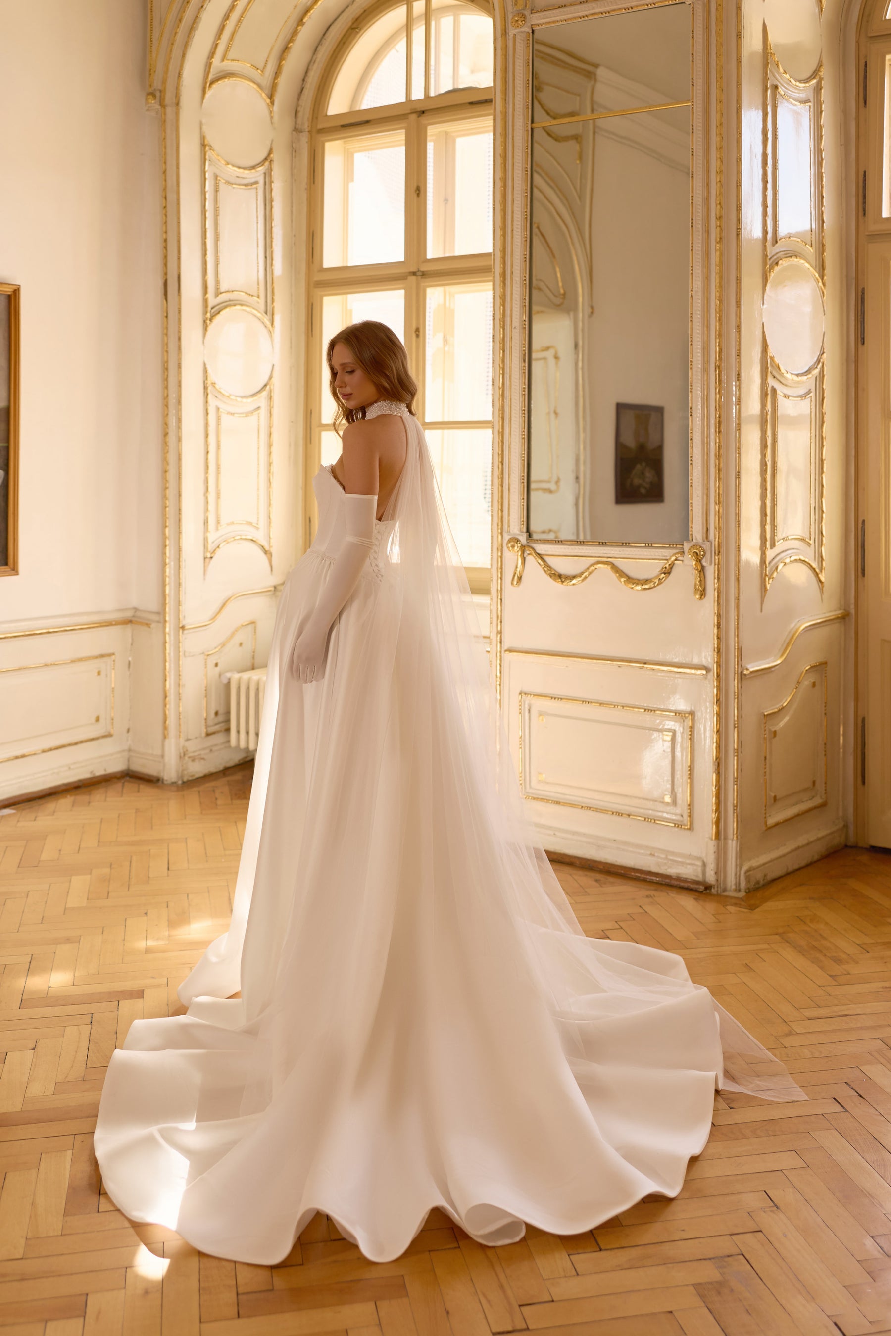 Ivory wedding dress with a low open back, fitted bodice, and sweeping satin train