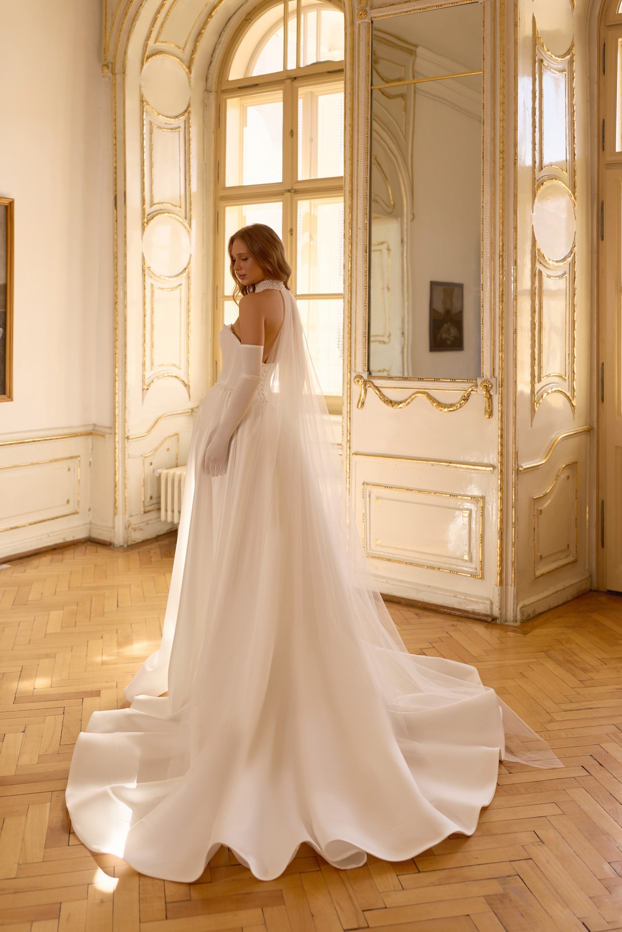 Ivory wedding dress with a low open back, fitted bodice, and sweeping satin train