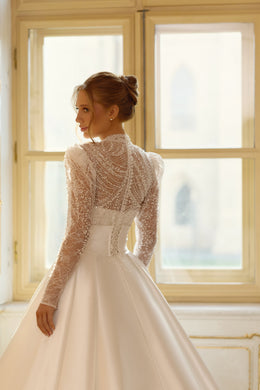 Sheer beaded long-sleeve back and defined waist on an ivory ball gown wedding dress