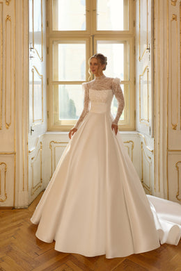 Ivory ball gown wedding dress with a high illusion neckline, beaded bodice, long sleeves, and train