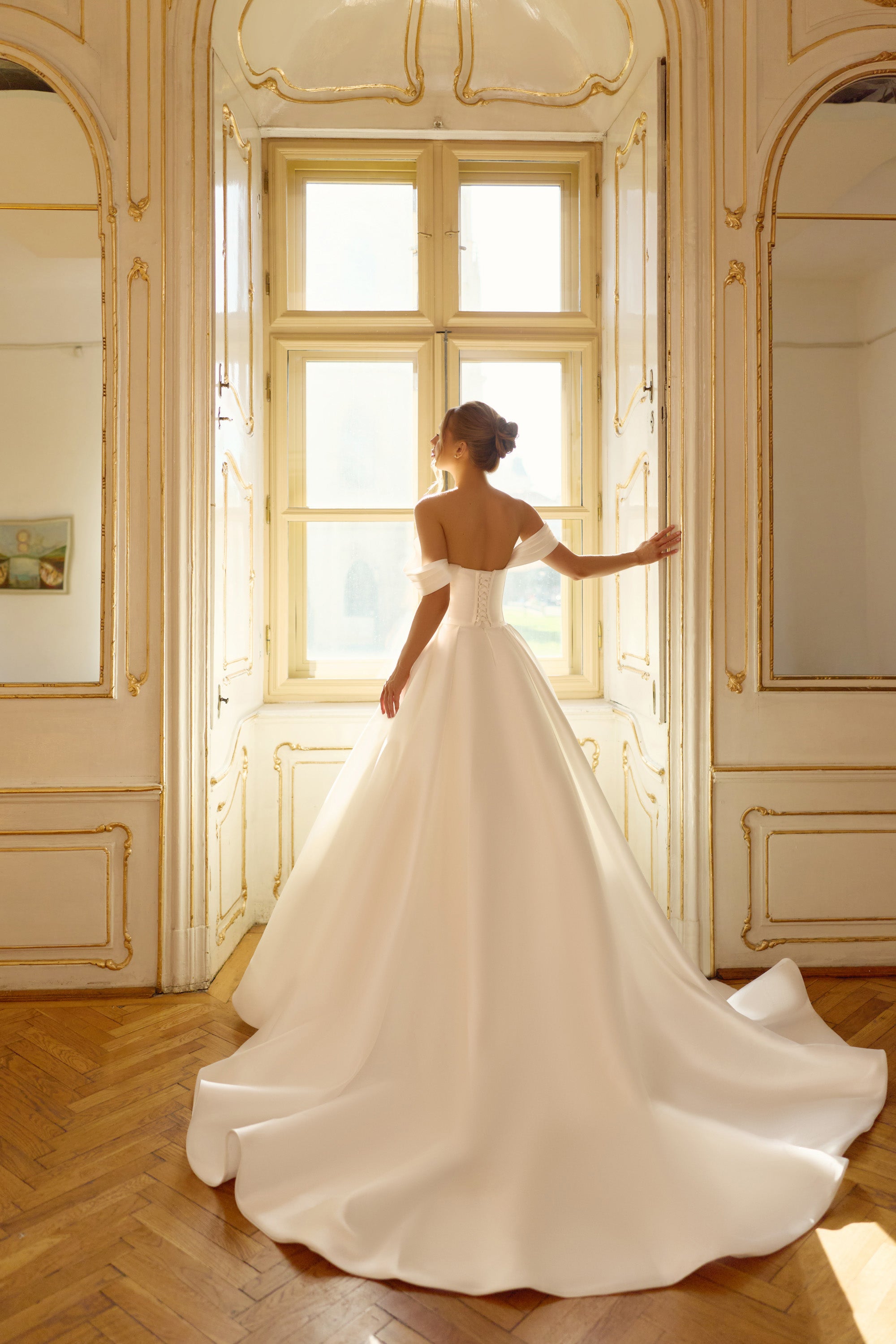 Open upper back and full satin skirt with a sweeping train on an ivory ball gown wedding dress