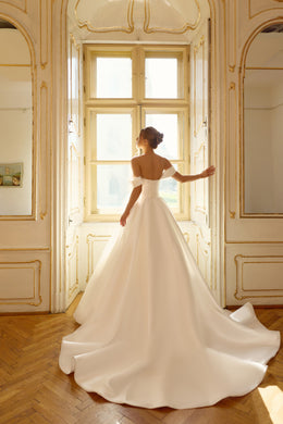 Open upper back and full satin skirt with a sweeping train on an ivory ball gown wedding dress