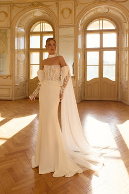Ivory wedding dress with a strapless lace corset bodice, fitted skirt, flowing cape, and long train