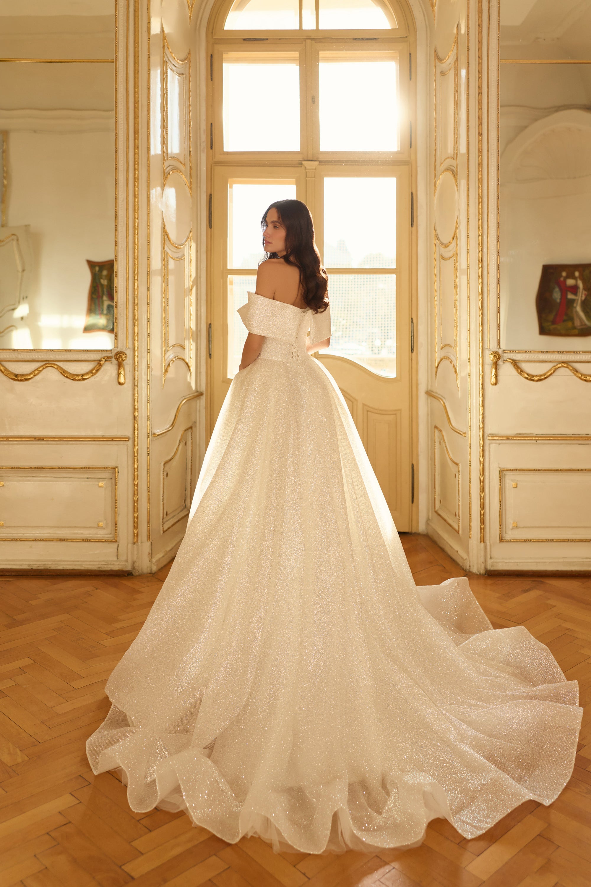 Glittering ivory wedding dress with an off-the-shoulder back, full ball-gown skirt, and long scalloped train