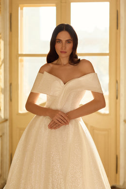 Close-up of an ivory wedding dress bodice with an off-the-shoulder neckline and shimmering textured fabric