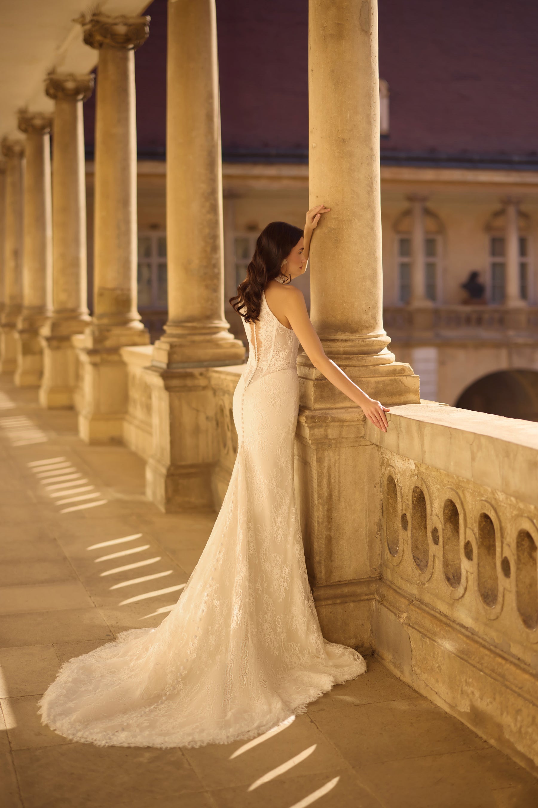 Open-back ivory lace wedding dress with a fitted mermaid silhouette and long scalloped train