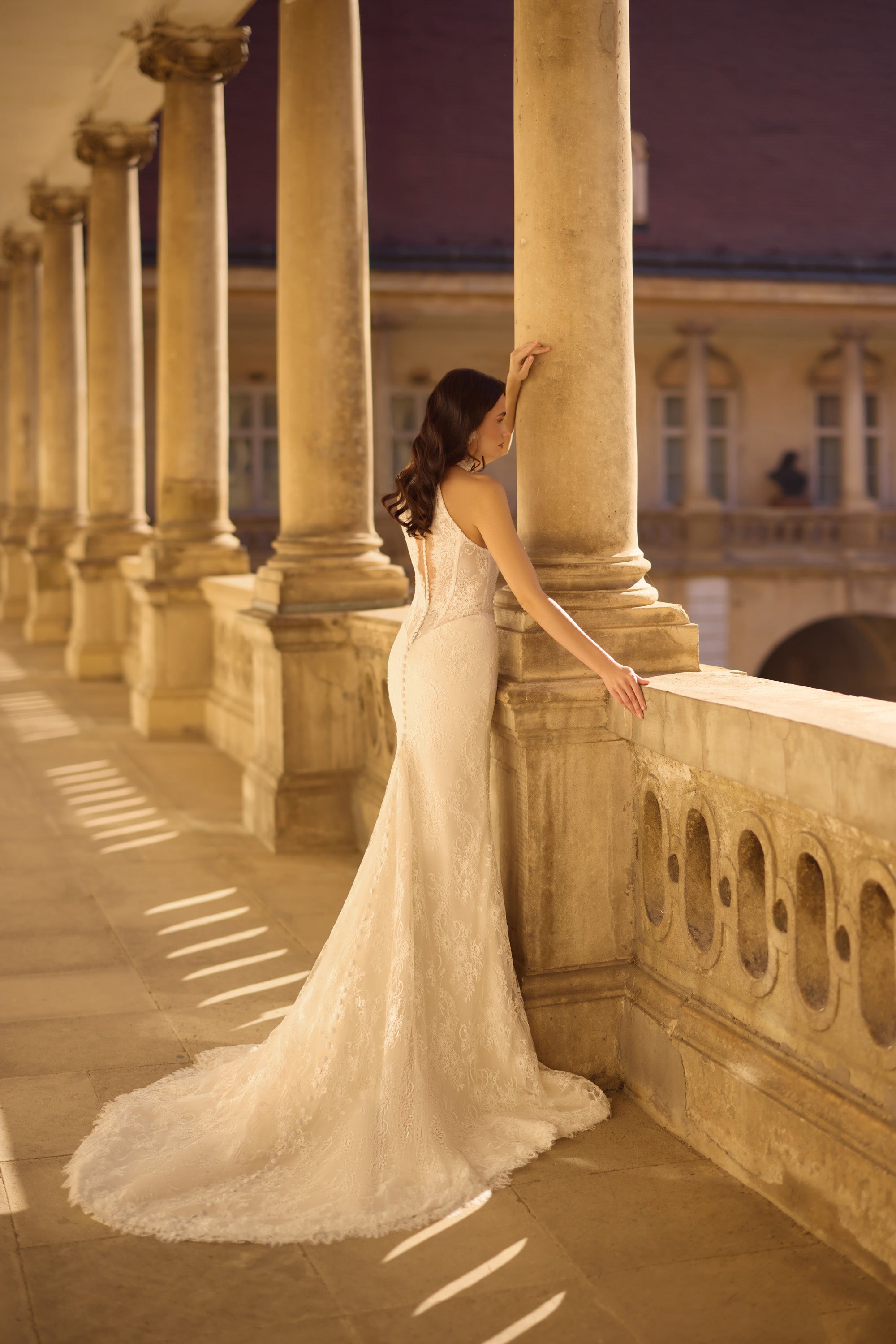 Open-back ivory lace wedding dress with a fitted mermaid silhouette and long scalloped train