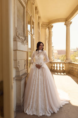 Ivory ball gown wedding dress with a high neckline, long lace sleeves, and a full floor-length skirt