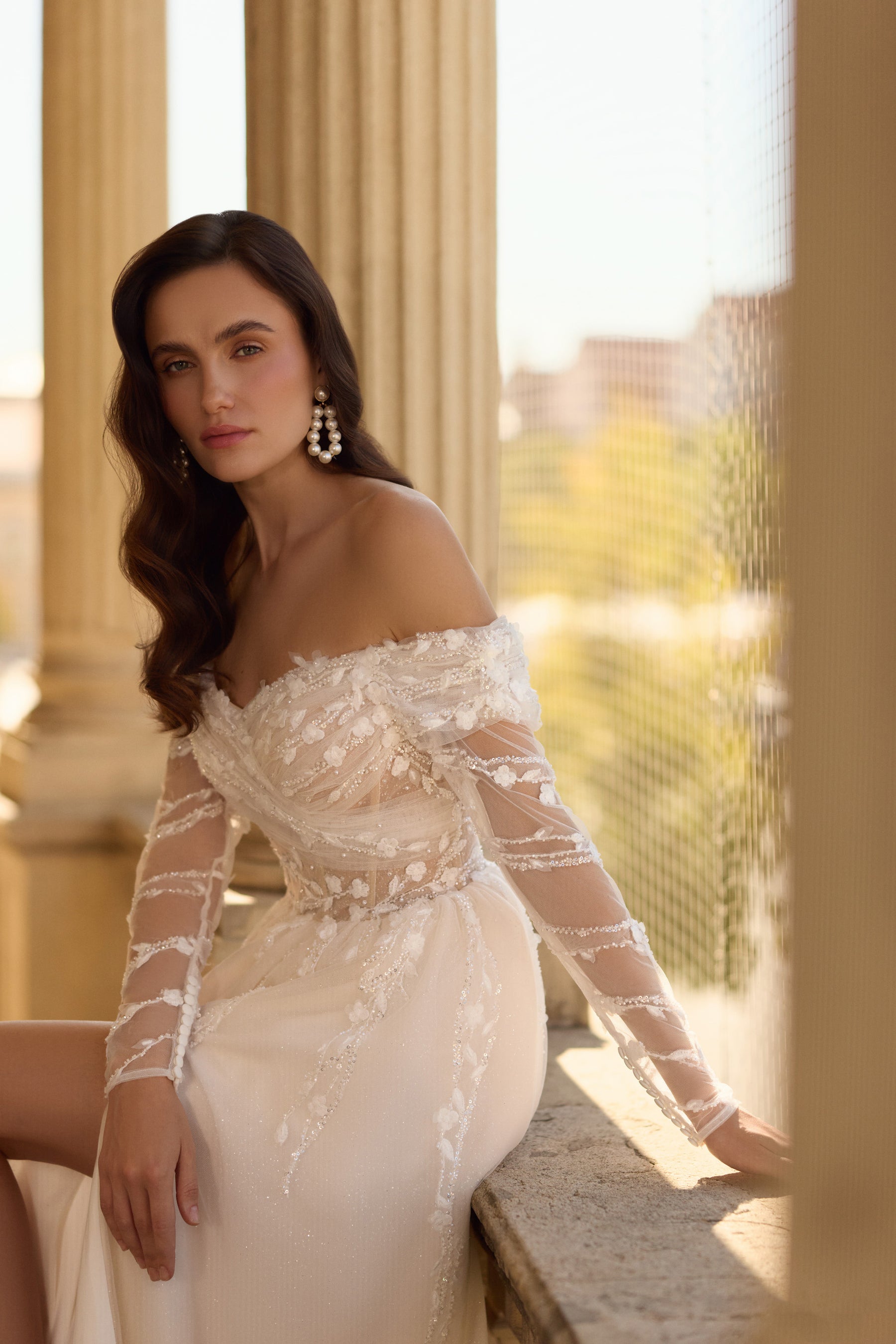 Close-up of an ivory wedding dress with floral lace bodice, off-the-shoulder neckline, and sheer sleeves