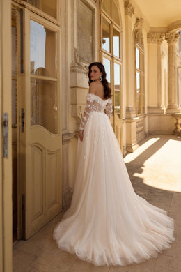 Flowing ivory wedding dress with a low open back, floral lace sleeves, and a long tulle train