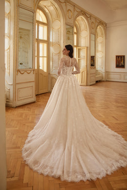 Lace-backed ivory wedding dress with sheer long sleeves, a full skirt, and an extended train