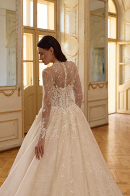 Close-up of the sheer lace back, covered buttons, and full skirt on an ivory wedding dress