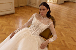 Ivory wedding dress featuring floral lace appliqués, a sheer illusion neckline, and fitted long sleeves