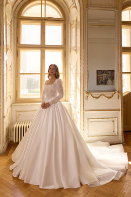Ivory ball gown wedding dress with a beaded bodice, long sheer sleeves, and a full satin skirt