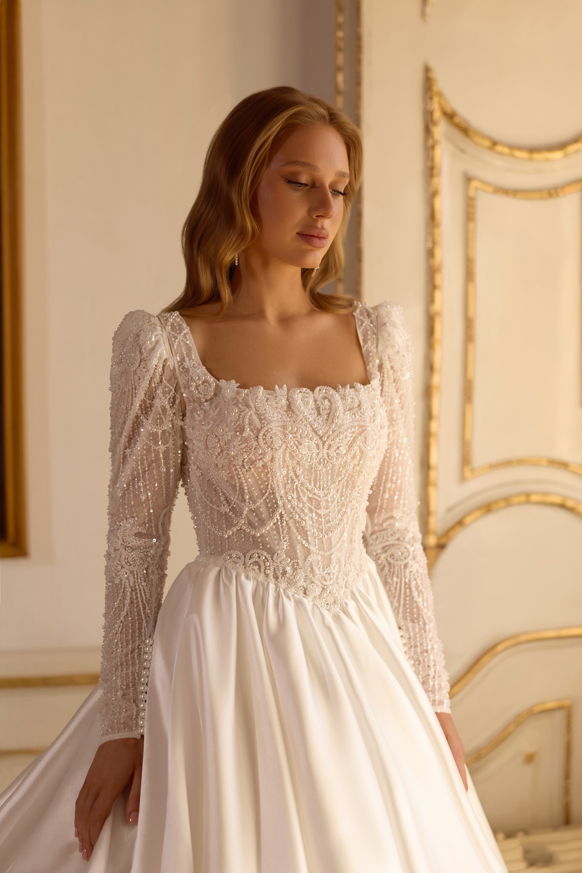 Ivory wedding dress with a square neckline, sheer beaded long sleeves, and a gathered full skirt