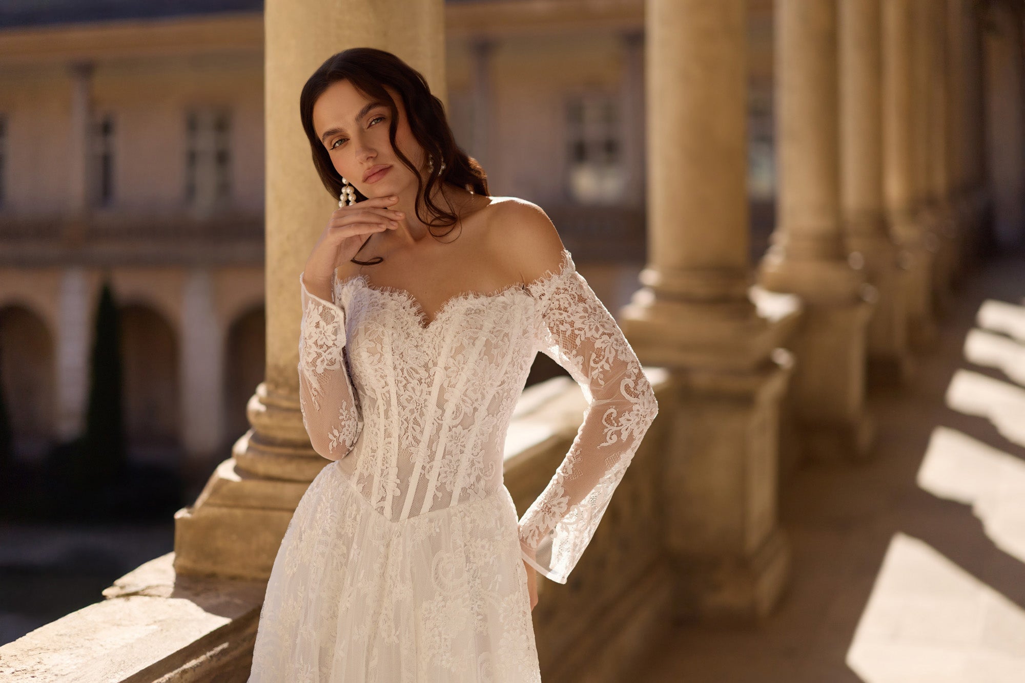 Fitted ivory wedding dress bodice with off-the-shoulder lace sleeves and a structured waist