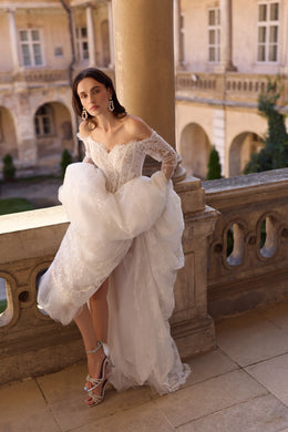 Ivory lace wedding dress with off-the-shoulder sleeves, flowing skirt, and layered overskirt