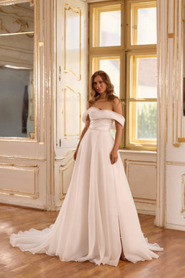 Ivory wedding dress with an off-the-shoulder draped bodice, flowing A-line skirt, and sweeping train