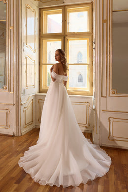 Side view of an ivory wedding dress with an off-the-shoulder neckline, bare upper back, and flowing train