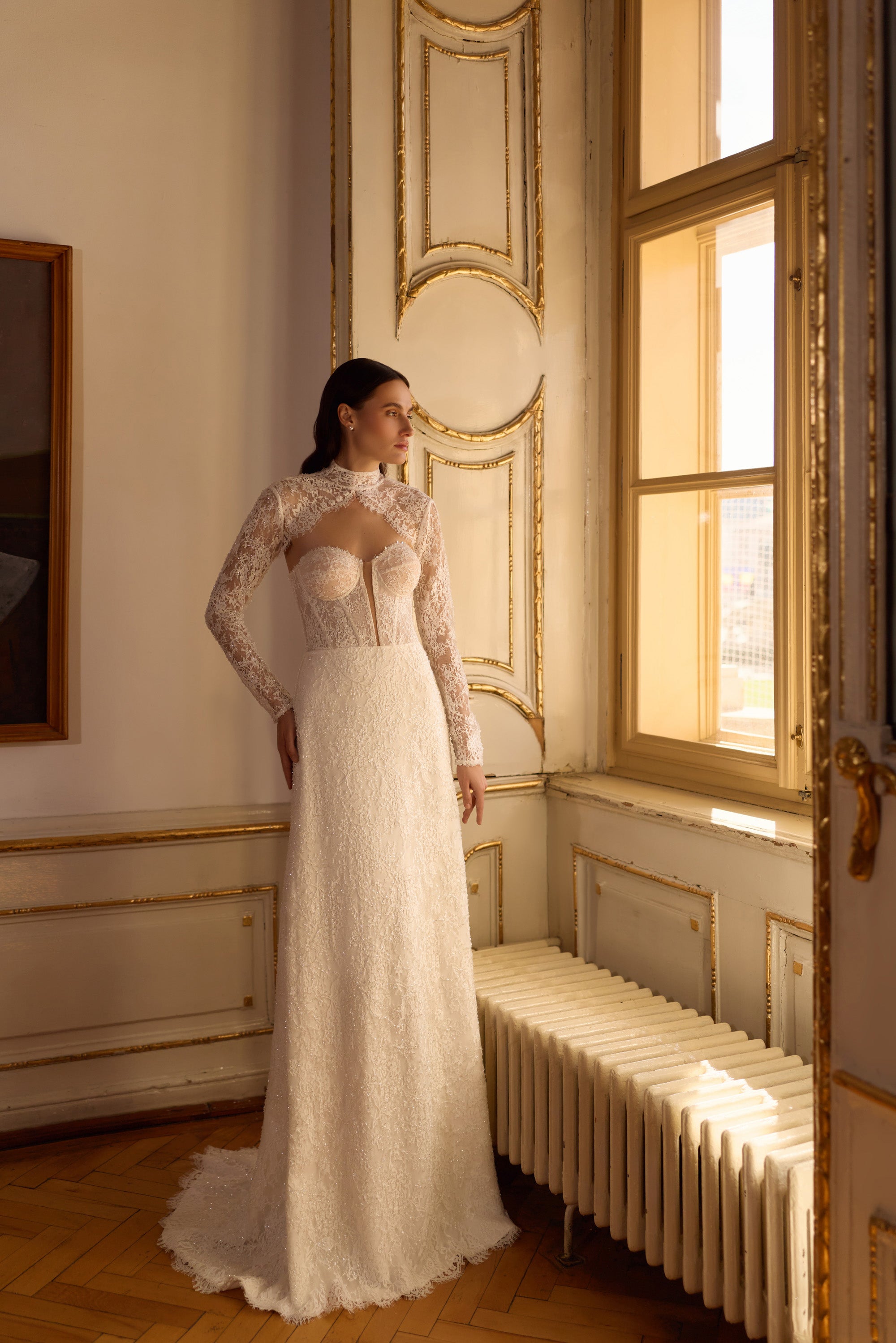 Ivory sheath wedding dress with long lace sleeves, high neckline, fitted bodice, and trailing train