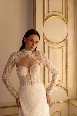 Ivory wedding dress with a strapless sweetheart bodice shown beneath a detachable long-sleeve lace bolero