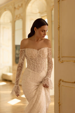 Detailed ivory wedding dress bodice with draped beadwork, an off-shoulder neckline, lace sleeves, and fitted skirt