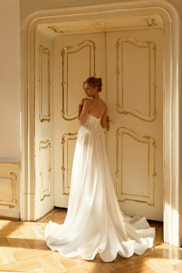 Flowing ivory wedding dress with a strapless bodice, open back, and full rippling train