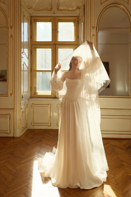 Full-length ivory A-line wedding dress with puff sleeves, flowing skirt, and long train