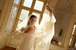 Ivory wedding dress with a straight neckline and puff sleeves beneath a sheer dotted veil