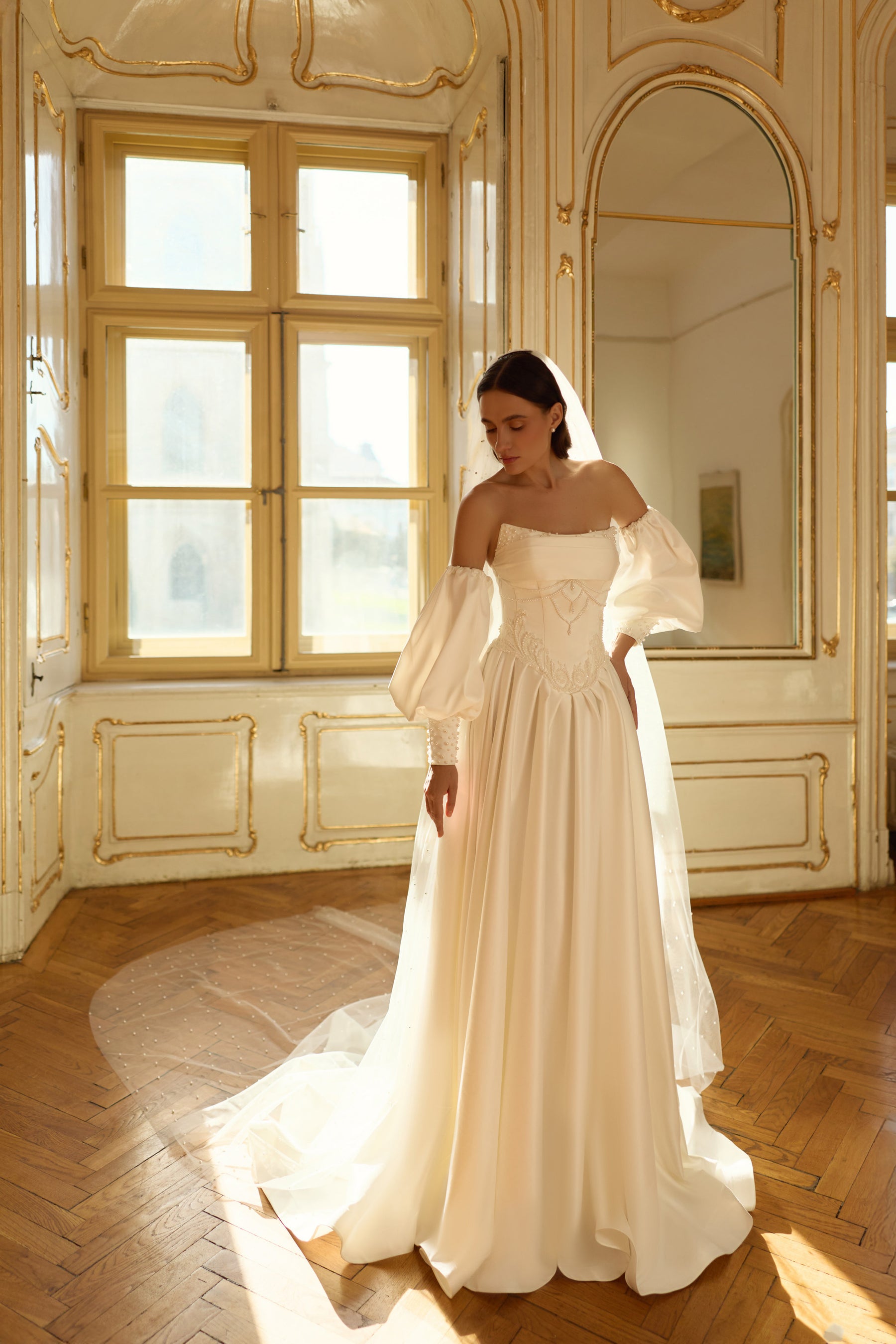 Ivory A-line wedding dress with puff sleeves, embellished waist detail, and a sweeping train