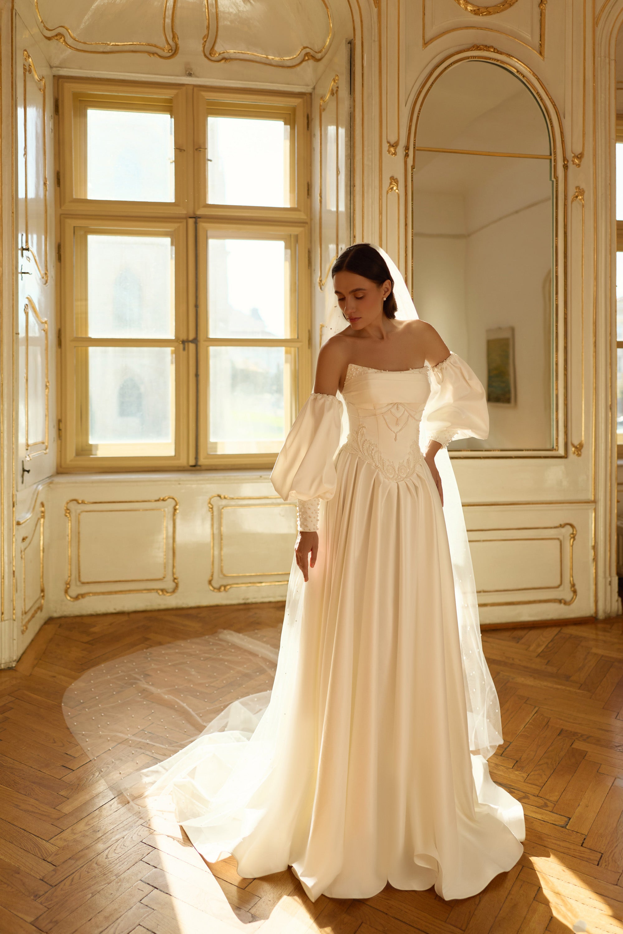 Ivory A-line wedding dress with puff sleeves, embellished waist detail, and a sweeping train