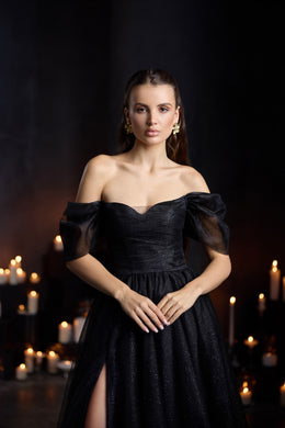 Black A-line evening dress with an off-the-shoulder neckline, sheer puff sleeves, sparkling bodice, and thigh slit